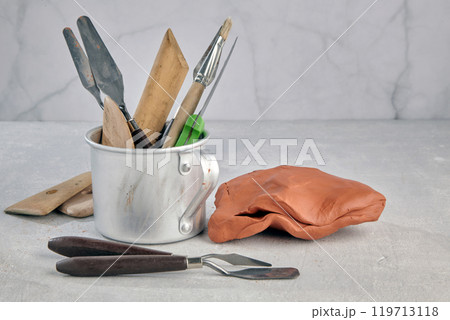 mug with many tools for sculpting and modeling and pieces of clay and plasticine on a stone table of a sculptor's workshop mug with many tools for sculpting and modeling and pieces of clay and plasticine on a stone table of a sculptor's workshop 119713118