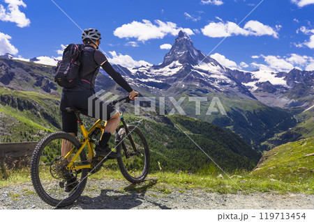 Mountain bike in Swiss Alps. Sportsman with bicycle with stunning view of Matterhorn. famous walking trail route Five lakes near Zermatt. Switzerland Mountain bike in Swiss Alps. Sportsman with bicycle with stunning view of Matterhorn. famous walking trail route Five lakes near Zermatt. Switzerland 119713454