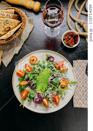 Fresh salad with avocado, grilled shrimp, baby greens, and cherry tomatoes served with red wine Fresh salad with avocado, grilled shrimp, baby greens, and cherry tomatoes served with red wine 119714094