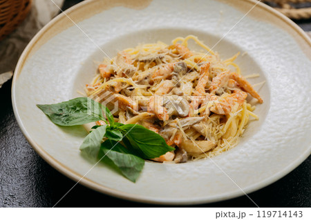 Creamy pasta with shrimp, mushrooms, Parmesan, and fresh basil, served in an elegant setting 119714143