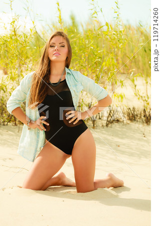 Young woman posing in grassy dune 119714260