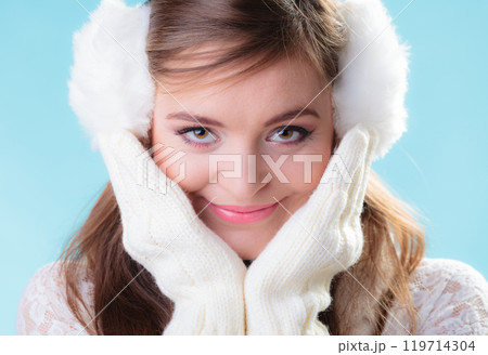 Happy woman in white earmuffs on blue 119714304