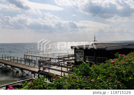 Seascape with sailing boat in the distance and pier 119715129