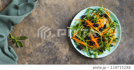 Vegetarian salad with prunes, herbs and carrots on a plate top view web banner 119715288
