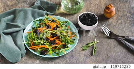 Delicious salad of carrots, arugula and prunes on a plate on the table web banner Delicious salad of carrots, arugula and prunes on a plate on the table web banner 119715289