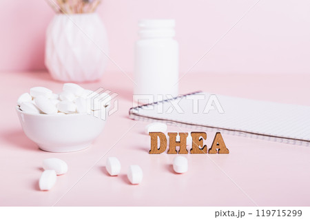 Hormonal supplement DHEA in tablets and a notebook on the table 119715299