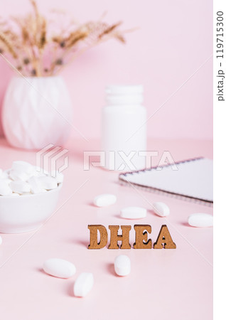 Hormonal supplement DHEA in tablets and a notebook on the table vertical view 119715300