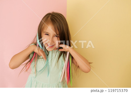 A sweet adorable girl adjusts her dyed bright colored hair. Artificial Hair Extensions A sweet adorable girl adjusts her dyed bright colored hair. Artificial Hair Extensions 119715370