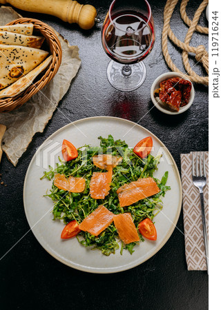 Gourmet arugula salad with smoked salmon and cherry tomatoes, served with red wine and rustic bread Gourmet arugula salad with smoked salmon and cherry tomatoes, served with red wine and rustic bread 119716244