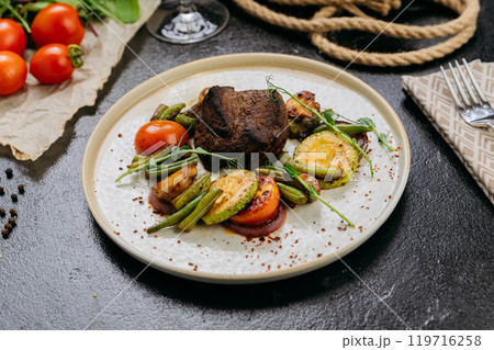 Grilled beef steak with vegetables and herbs, served with wine in a rustic presentation 119716258