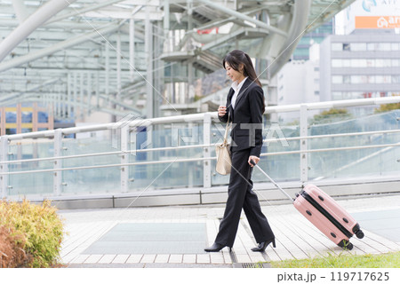 スーツケースを牽いて名古屋に出張する若いビジネスウーマン スーツケースを牽いて名古屋に出張する若いビジネスウーマン 119717625