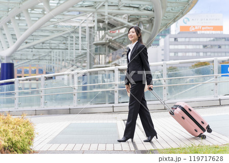 スーツケースを牽いて名古屋に出張する若いビジネスウーマン スーツケースを牽いて名古屋に出張する若いビジネスウーマン 119717628