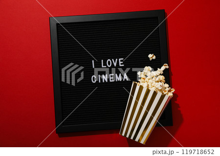 Black letter board and paper cup with popcorn on red background, top view 119718652