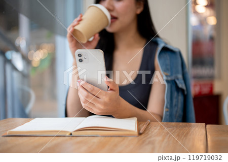 A close-up of a woman reading text messages on her smartphone while enjoying coffee in a coffee shop A close-up of a woman reading text messages on her smartphone while enjoying coffee in a coffee shop 119719032