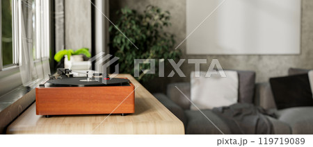A vintage wooden record vinyl player on a wooden cabinet by the window in a contemporary living room 119719089