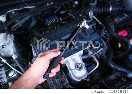 Auto mechanic hand holding torque wrench or socket wrench 119719115