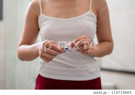 A close-up of a woman in pajamas taking medicine in the bathroom. A close-up of a woman in pajamas taking medicine in the bathroom. 119719665