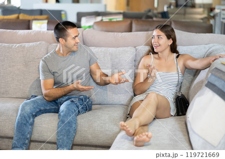 Happy young couple choosing a soft new sofa in furniture store 119721669