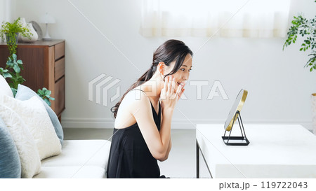 室内で鏡を見てスキンケアする女性 119722043