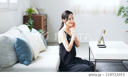 室内で鏡を見てスキンケアする女性 119722053