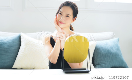 室内で鏡を見てスキンケアする女性 119722107