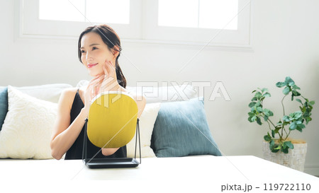 室内で鏡を見てスキンケアする女性 室内で鏡を見てスキンケアする女性 119722110