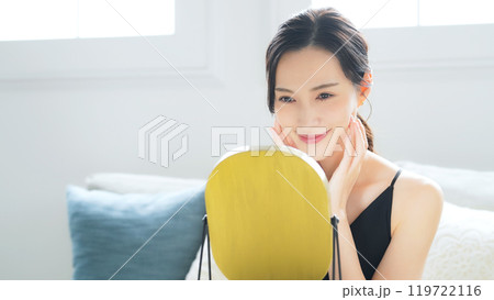 室内で鏡を見てスキンケアする女性 室内で鏡を見てスキンケアする女性 119722116