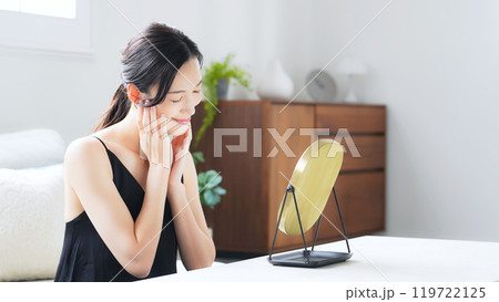 室内で鏡を見てスキンケアする女性 119722125