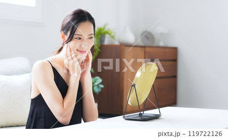 室内で鏡を見てスキンケアする女性 119722126