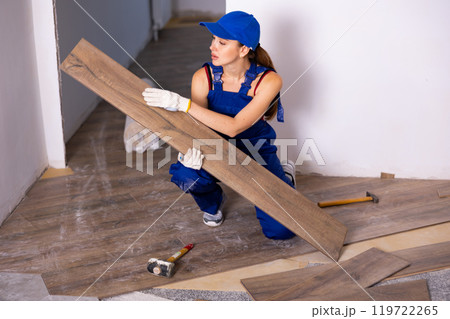 Female repairer installing laminate flooring in apartment Female repairer installing laminate flooring in apartment 119722265