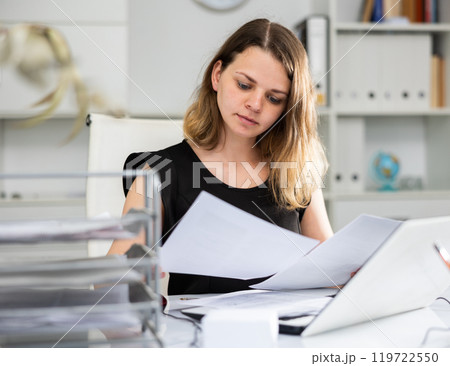 Woman bookkeeper doing paperwork in office 119722550