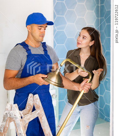 Plumber installing shower for woman in apartment Plumber installing shower for woman in apartment 119722612