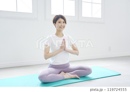 ヨガマットの上で座禅をするミドルエイジの女性　カメラ目線 119724555