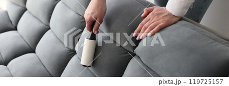 Woman uses roller to remove pellets from grey soft couch Woman uses roller to remove pellets from grey soft couch 119725157