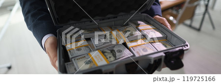 Rich businessman holds big case with counted stacks of money 119725166