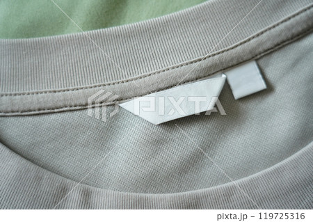 Close up of blank white clothing care label on shirt fabric background. Close up of blank white clothing care label on shirt fabric background. 119725316