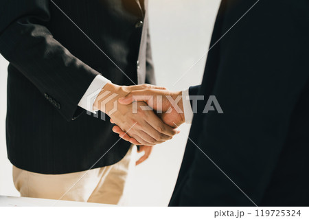 Business people in office suits standing and shaking hands, close-up. Business communication concept. Handshake and marketing. Business people in office suits standing and shaking hands, close-up. Business communication concept. Handshake and marketing. 119725324