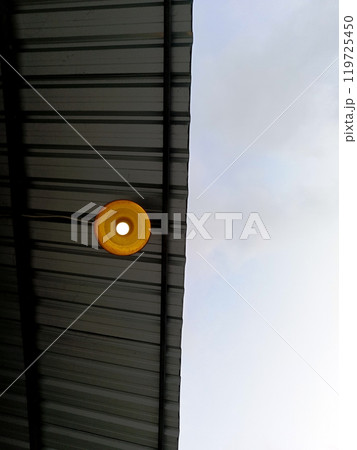 A light bulb of a lamp light hanging under a galvanized steel roof 119725450