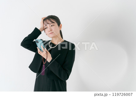 スマホを持って考える喪服の女性 119726007