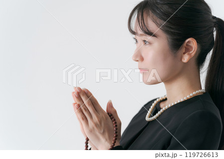手を合わせる喪服の女性 119726613