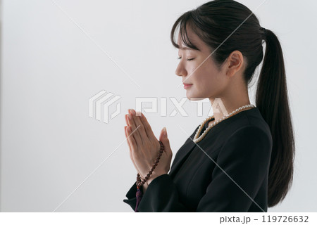 手を合わせる喪服の女性の横顔 119726632