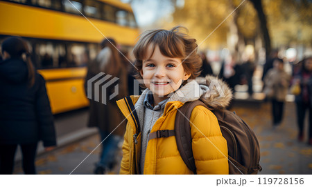 Smiling caucasian schoolboy with a backpack is standing at the school bus. Elementary school. Journey to Knowledge. Concept back to school. Smiling caucasian schoolboy with a backpack is standing at the school bus. Elementary school. Journey to Knowledge. Concept back to school. 119728156