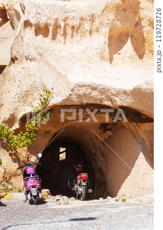 two rent scooters parked directly in front of a cave entrance in Cappadocia 119728726