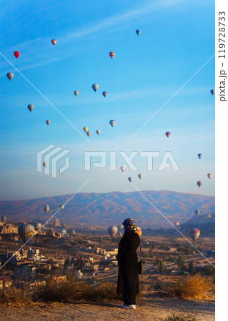 Person woman watch hot air balloons over a city in Cappadocia Person woman watch hot air balloons over a city in Cappadocia 119728733
