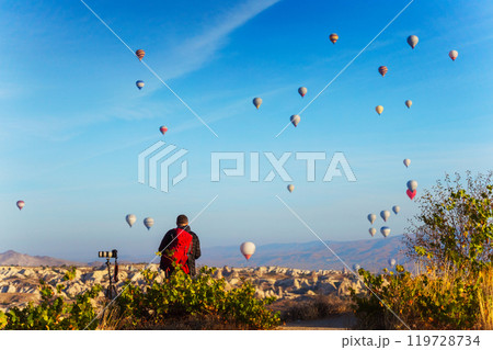 Photographer watch hot air balloons over a city in Cappadocia Photographer watch hot air balloons over a city in Cappadocia 119728734
