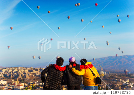 Three man guy watch hot air balloons over a city valley in Cappadocia 119728756
