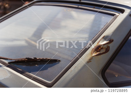 Closeup of a rusty car with a yellow light on its side 119728895