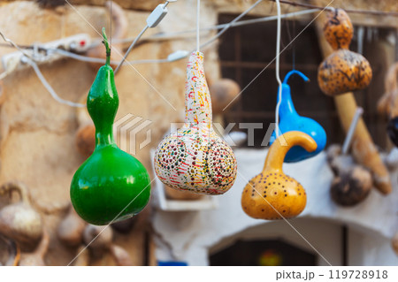 A bunch of vibrant, colorful lanterns gourds beautifully hanging from a string A bunch of vibrant, colorful lanterns gourds beautifully hanging from a string 119728918