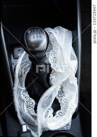 White lace women's panties near the gearshift lever in the car 119728947