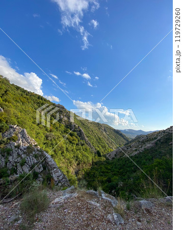 Scenic view of a lush green valley stretching under a vast blue sky, offering a breathtaking perspective of nature's tranquility. Rugged terrain and vibrant foliage invite explorers to immerse Scenic view of a lush green valley stretching under a vast blue sky, offering a breathtaking perspective of nature's tranquility. Rugged terrain and vibrant foliage invite explorers to immerse 119729260